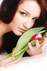 Beautiful brunette woman with flower on white bed