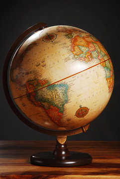 An antique globe on a table with a dark grey background