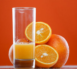 glass of orange juice with fruits near by