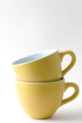 due tazzine gialle da caffè con piattini bianchi