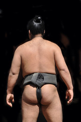 Lutteur de sumo avant le match, vu de dos, isolé sur fonds noir