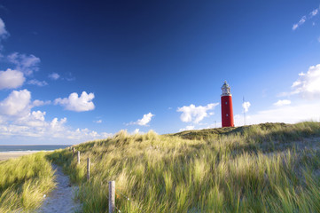 a red lighthousein the dunes with a blue sky in summer - 13385139