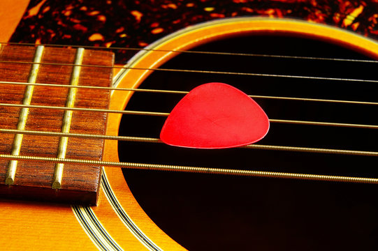 Closeup Of A Guitar Pick On Acoustic Guitar Strings