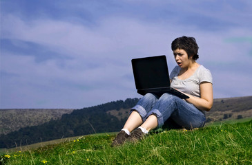 Surprised woman working on laptop outdoors