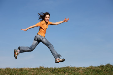 Girl jumping, running against blue sky