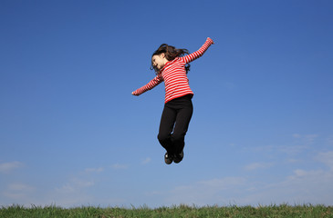 Girl jumping, running against blue sky