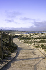 Railing and boardwalk over sand dunes and blue sky on the Califo