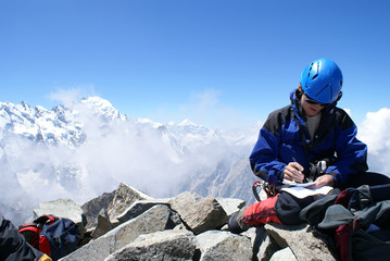 Climber writes records in a notebook on the top of mountain