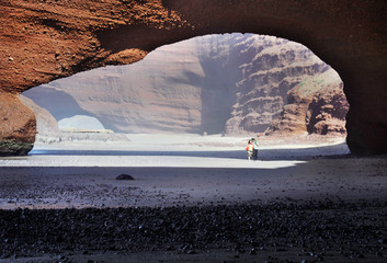 Young couple walking under arch rock formation
