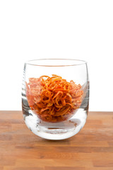 dried chopped red chilies in glass, white background
