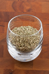 dried fennel seeds in glass on wooden table