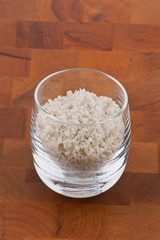 coarse grey sea salt in glass on wooden table