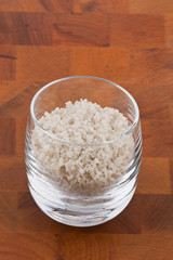 coarse grey sea salt in glass on wooden table