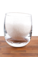 fleur de sel, white sea salt crystals in glass, white background
