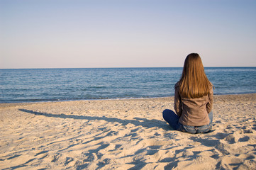 A young woman seating alone at the seaside