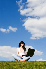 pretty woman with laptop on the green grass