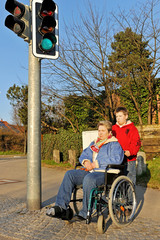 Junge schiebt Frau im Rollstuhl