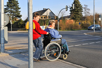 Fototapeta na wymiar Junge schiebt Frau im Rollstuhl