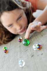 Young girl playing marbles - 13494975