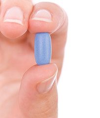Hand holding a blue pill close up.
