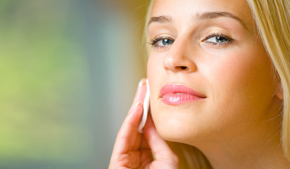 Portrait of young beautiful woman applying creme