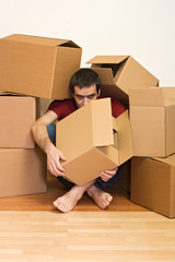 Man under cardboard boxes on the floor - moving concept