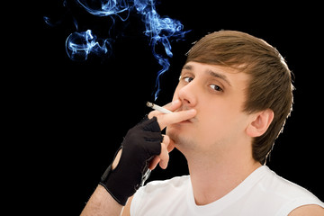 Obraz premium Young man smoking a cigarette. Isolated on black