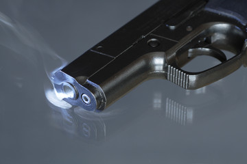 Automatic pistol after shooting on dark background