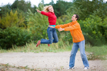 Fototapeta premium Happy Young Couple - jumping against a green tree