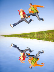 Happy young couple  jumping in sky above a green meadow