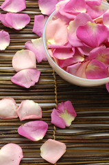 Bowl of rose petals on bamboo spa mats.