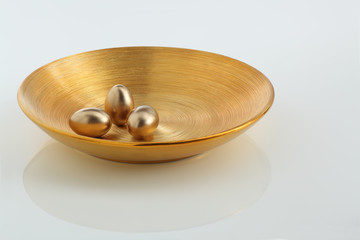 drei goldene Eier auf goldener Schale