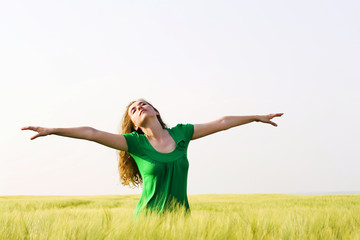 blond woman with open arms in a wheat field