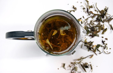 Close-up of teapot with green tea and tea leaves