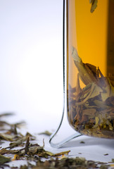 Closeup of teapot with green tea and tea leaves
