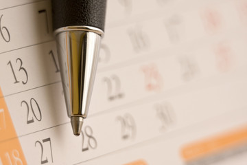 Planning future tasks on a calendar using a ballpoint pen.
