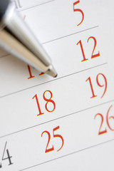 Planning future tasks on a calendar using a ballpoint pen.