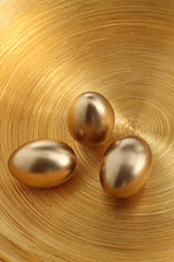 drei goldene Eier auf goldener Schale