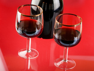 Glass of red wine with glass and bottle