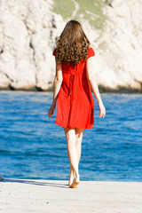 young girl in red dress on the sea