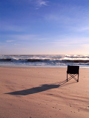 Isolated chair on the beach at sunrise