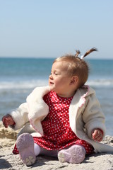 bébé fille assise devant la mer