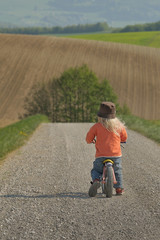 Kind mit Laufrad auf Feldweg