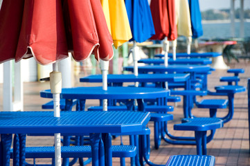 Fototapeta na wymiar Blue tables with colorful umbrellas