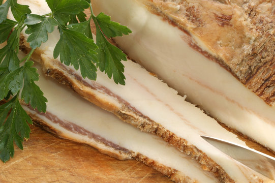 fetter Speck und Petersilie auf einem Holzbrett