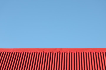 faîte de toiture en tôle ondulée rouge sur fond de ciel bleu