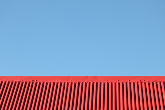 faîte de toiture en tôle ondulée rouge sur fond de ciel bleu