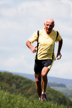 Älterer Mann beim joggen läuft über Wiese