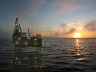 the drilling platform on sea on background of the setting sun