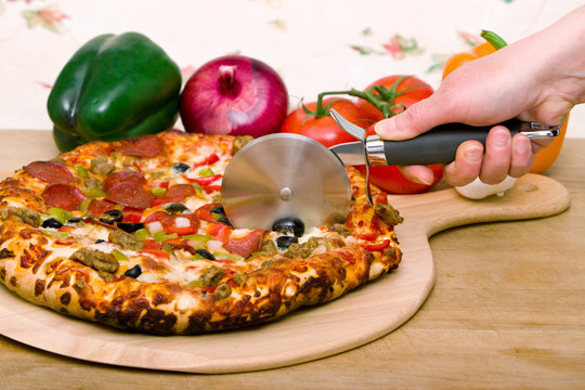 Cheese pizza cutting by wheel pizza cutter. Stock Photo by stockfilmstudio